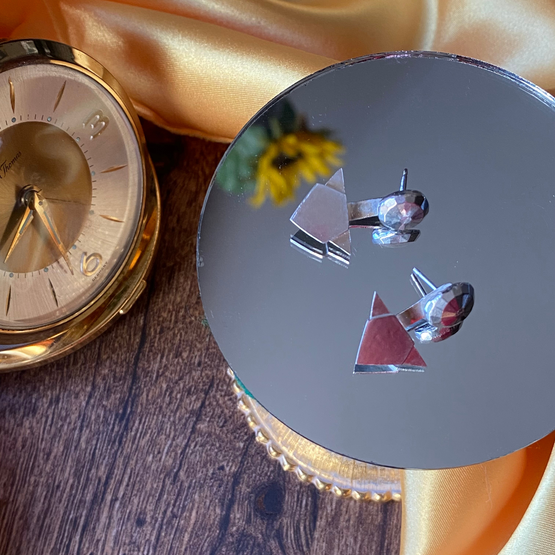 Gold watch and earrings displayed on a mirrored surface with a gold cloth background. Wild Sunflower Silver Handmade Jewelry