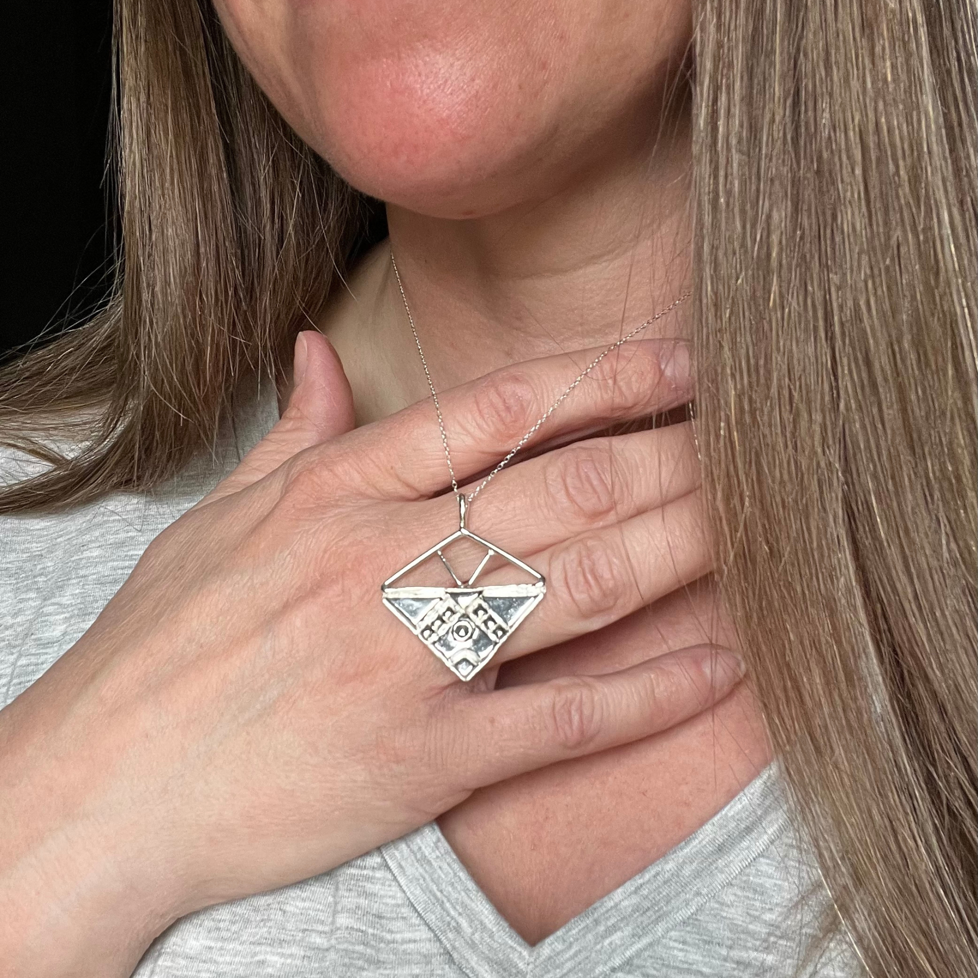 Silver geometric pendant necklace with small clear gems on gray backdrop. Wild Sunflower Silver Handmade Jewelry