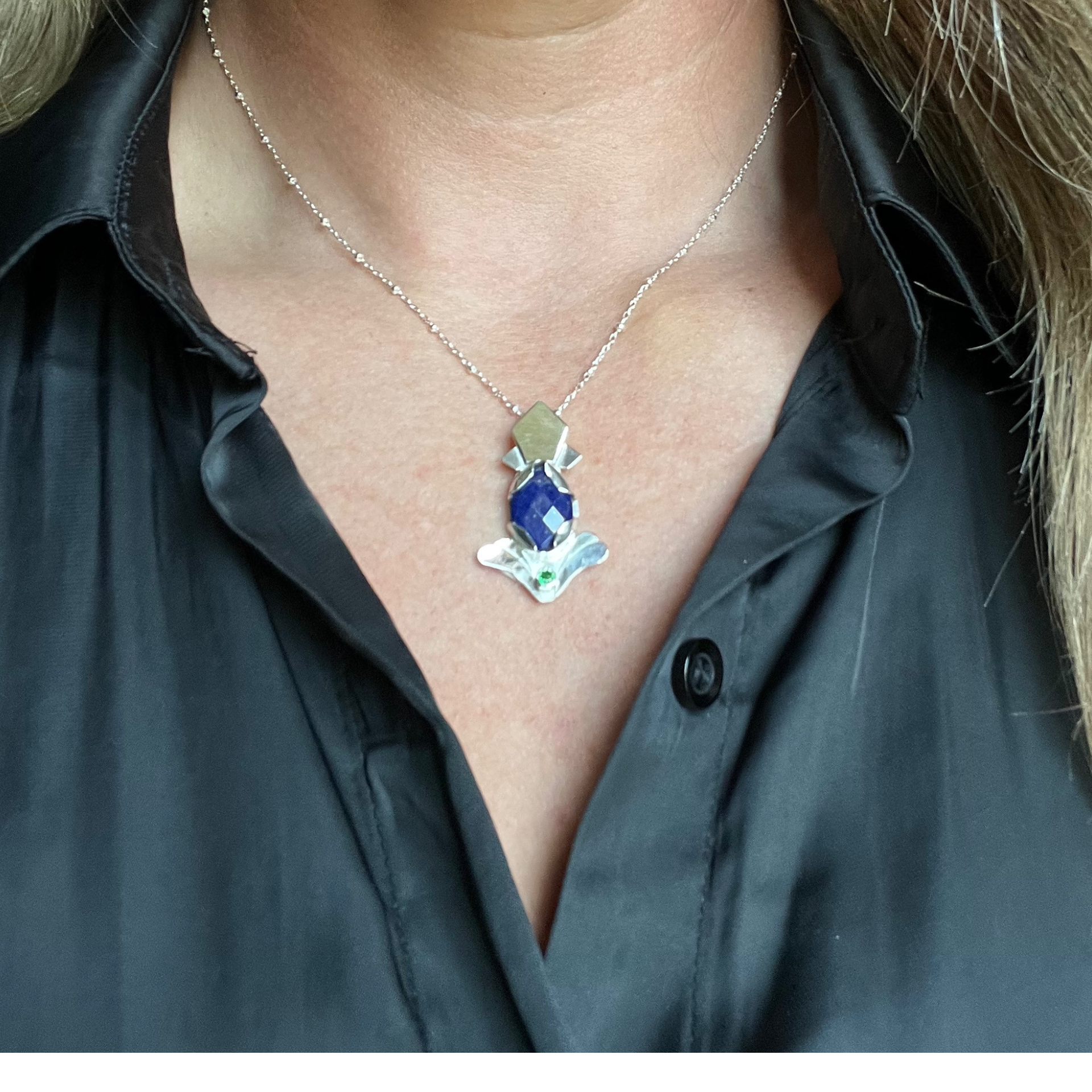 Silver necklace with a blue gem pendant, teardrop shape, with green accent. Wild Sunflower Silver Handmade Jewelry