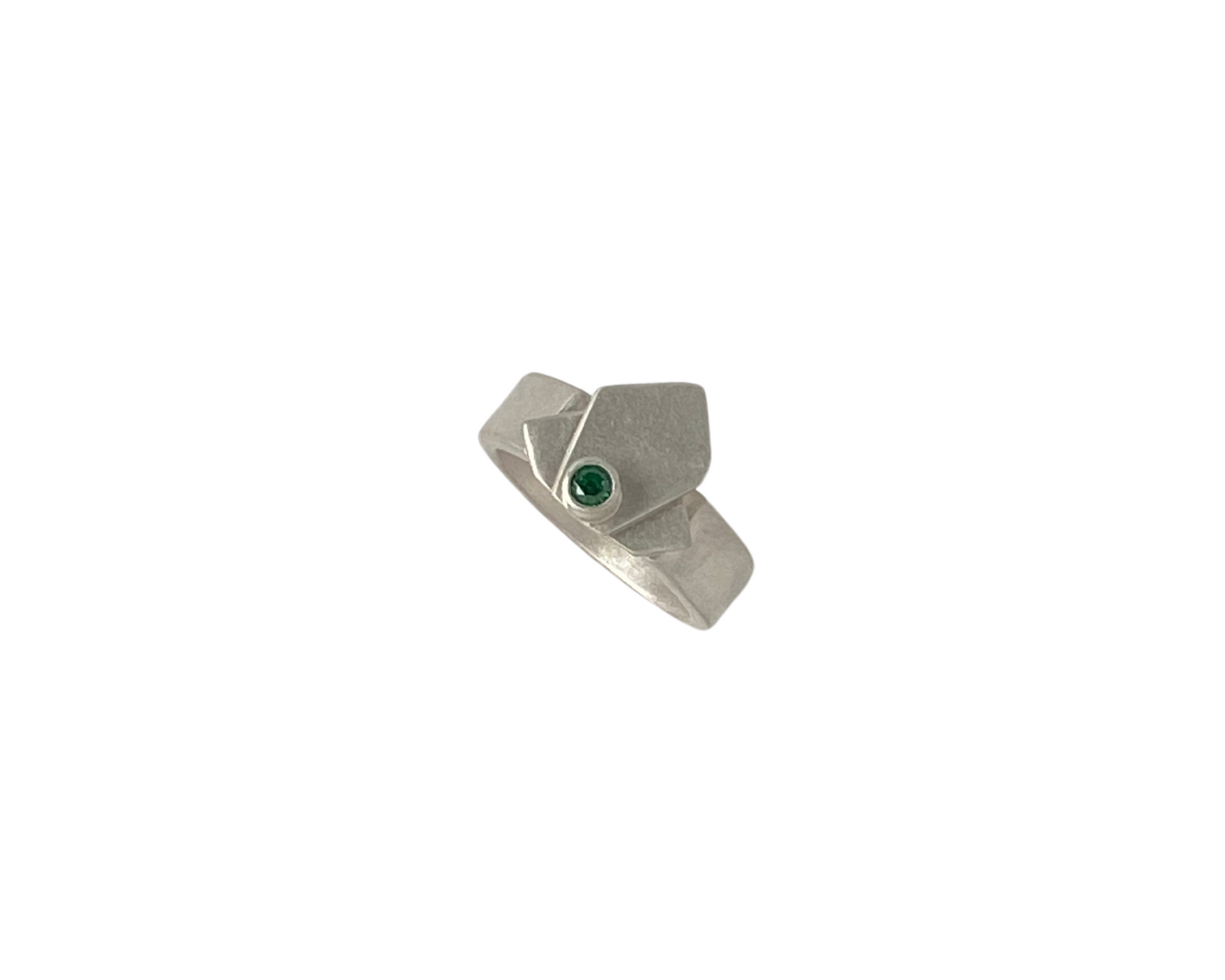 A silver geometric ring with a small green gemstone on a person's finger. Wild Sunflower Silver Handmade Jewelry