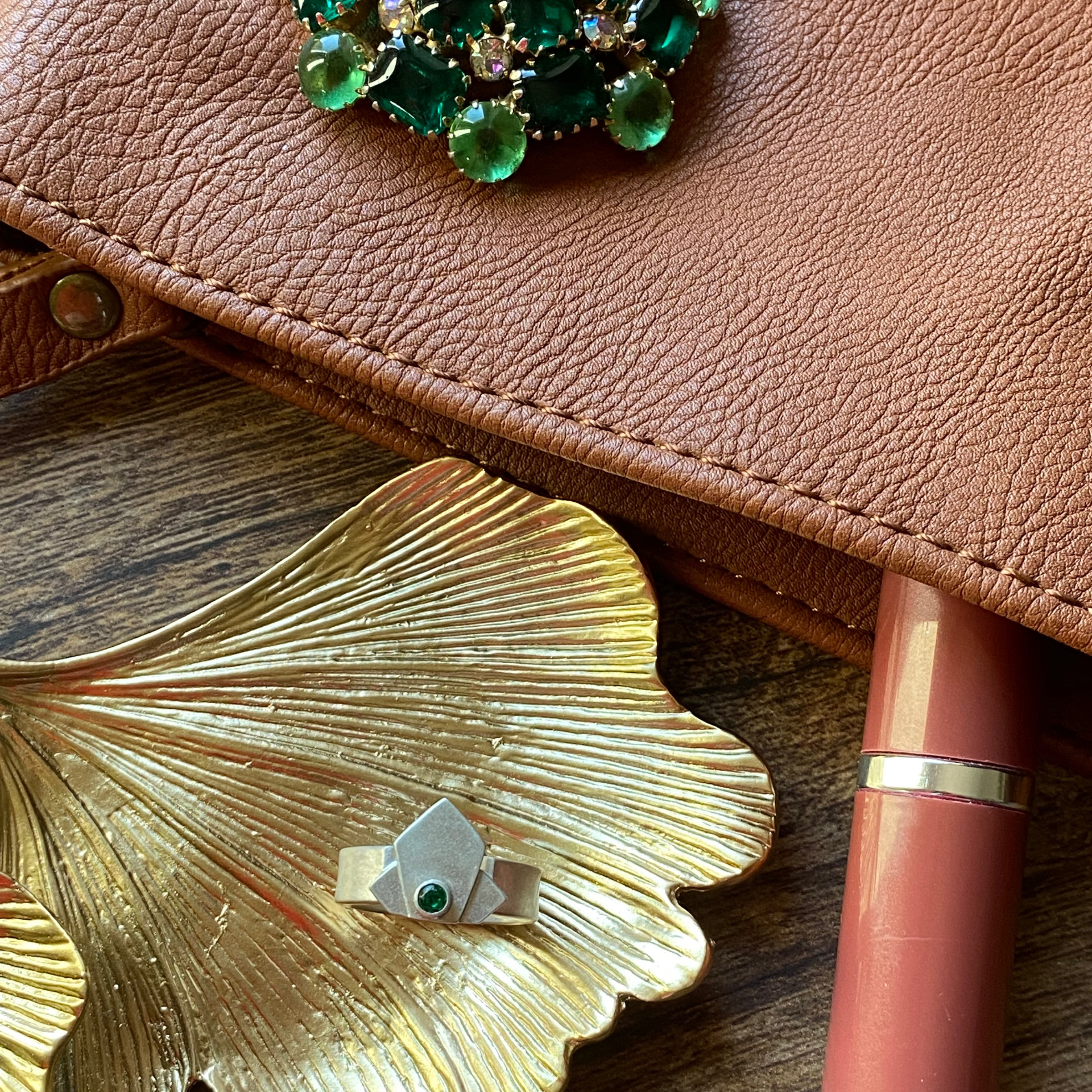 Leather clutch with jeweled brooch, gold leaf dish with ring, and lipstick. Wild Sunflower Silver Handmade Jewelry