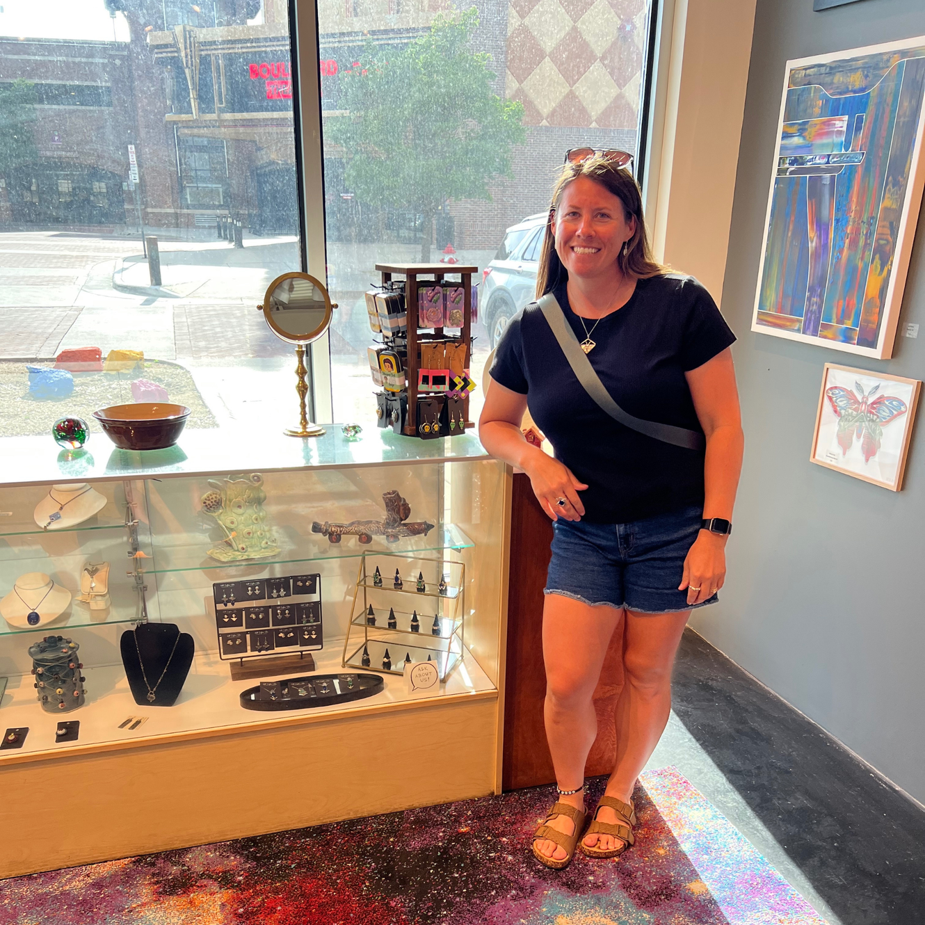 April Raile owner and designer standing by jewelry at Art Shoppe at City Arts in Wichita, Ks Wild Sunflower Silver 