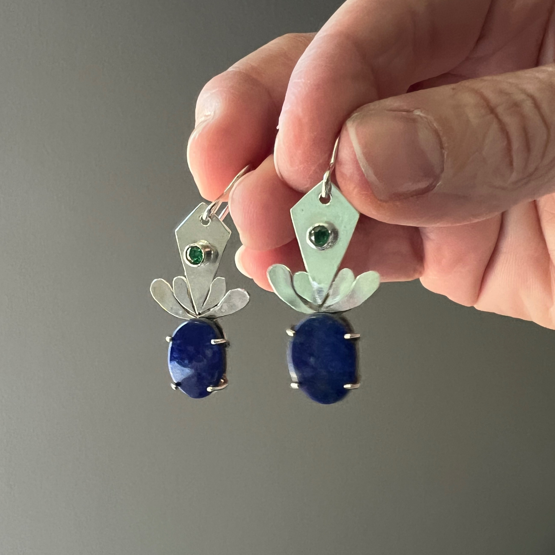 Close-up of an earring with a blue oval stone and a green gem,Wild Sunflower Silver Handmade Jewelry