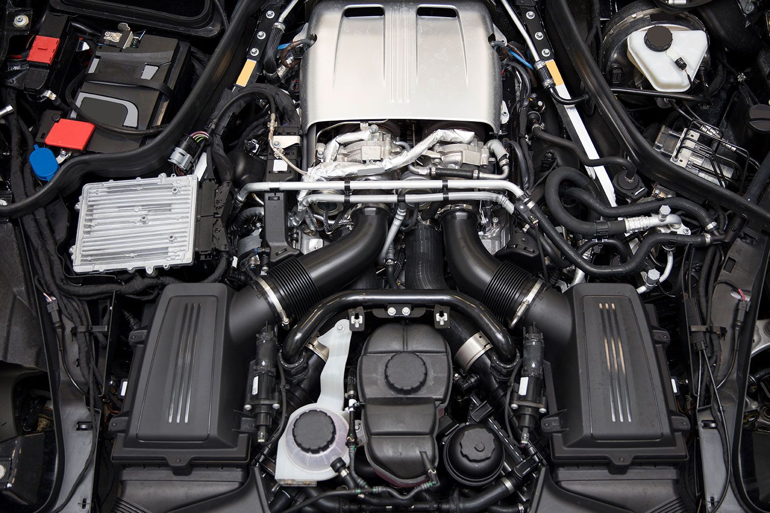 A close up of the engine of a car with the hood open.