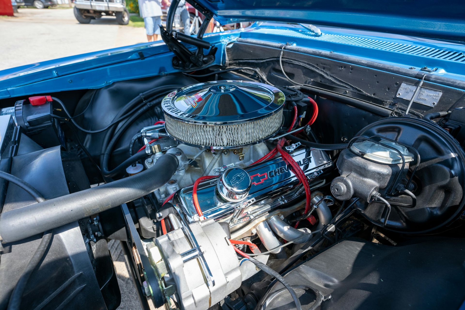 The engine of a blue car is shown with the hood open.