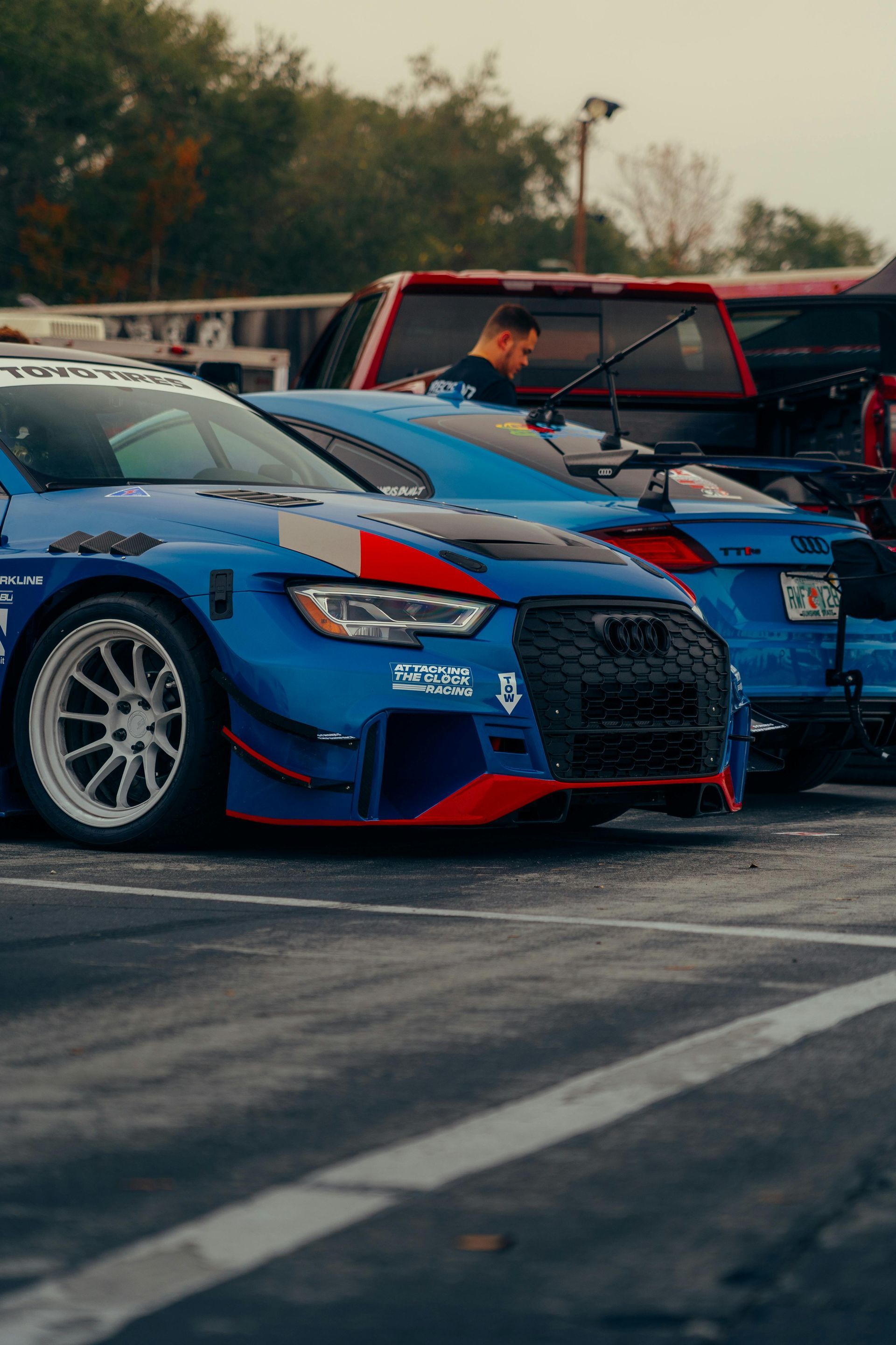 A row of blue cars are parked in a parking lot.