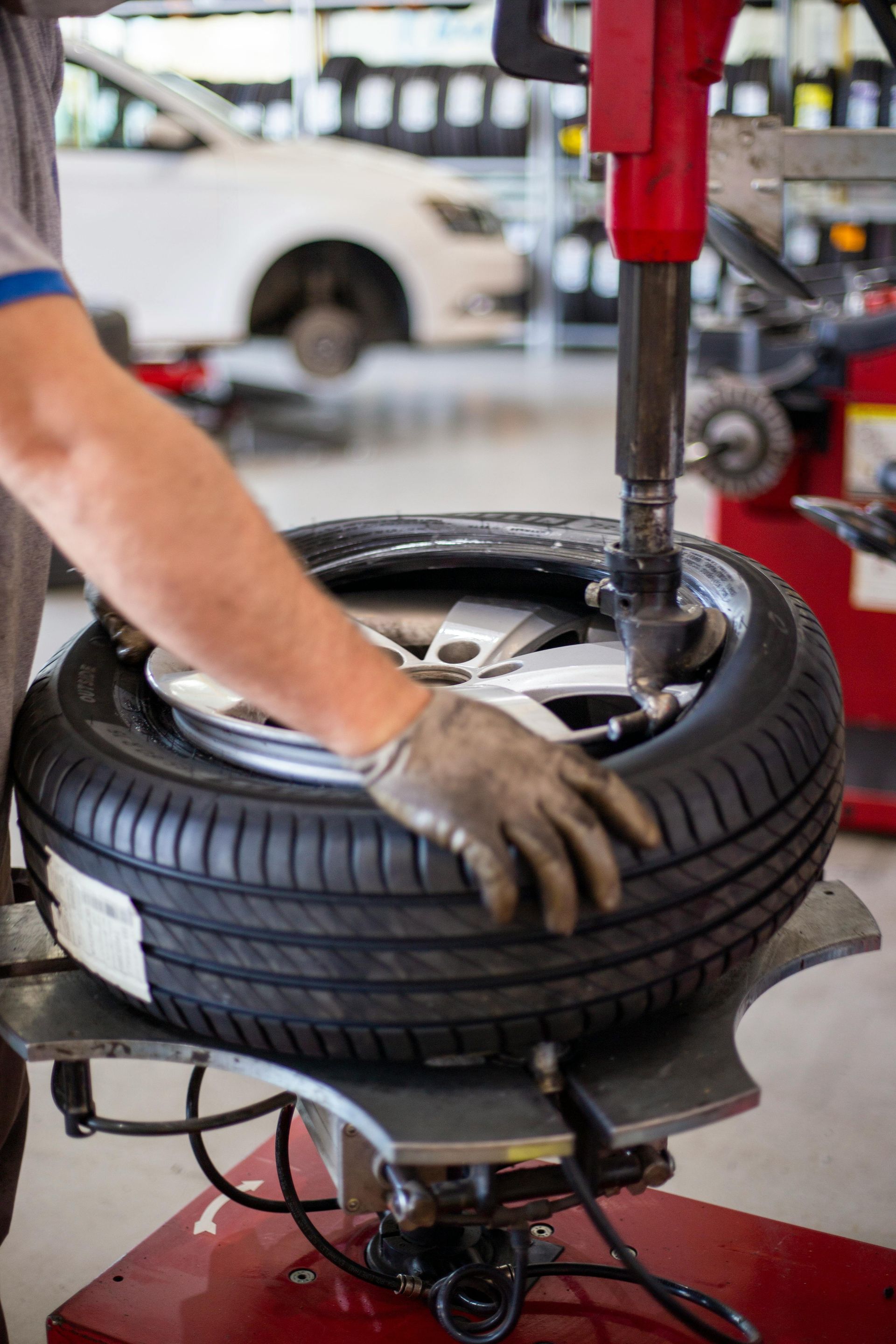 A man is changing a tire on a machine in a garage.