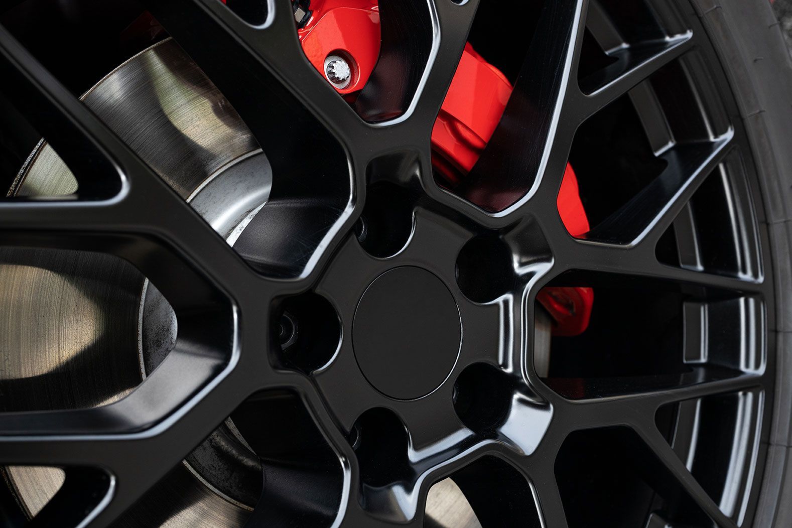 A close up of a black car wheel with red brake calipers