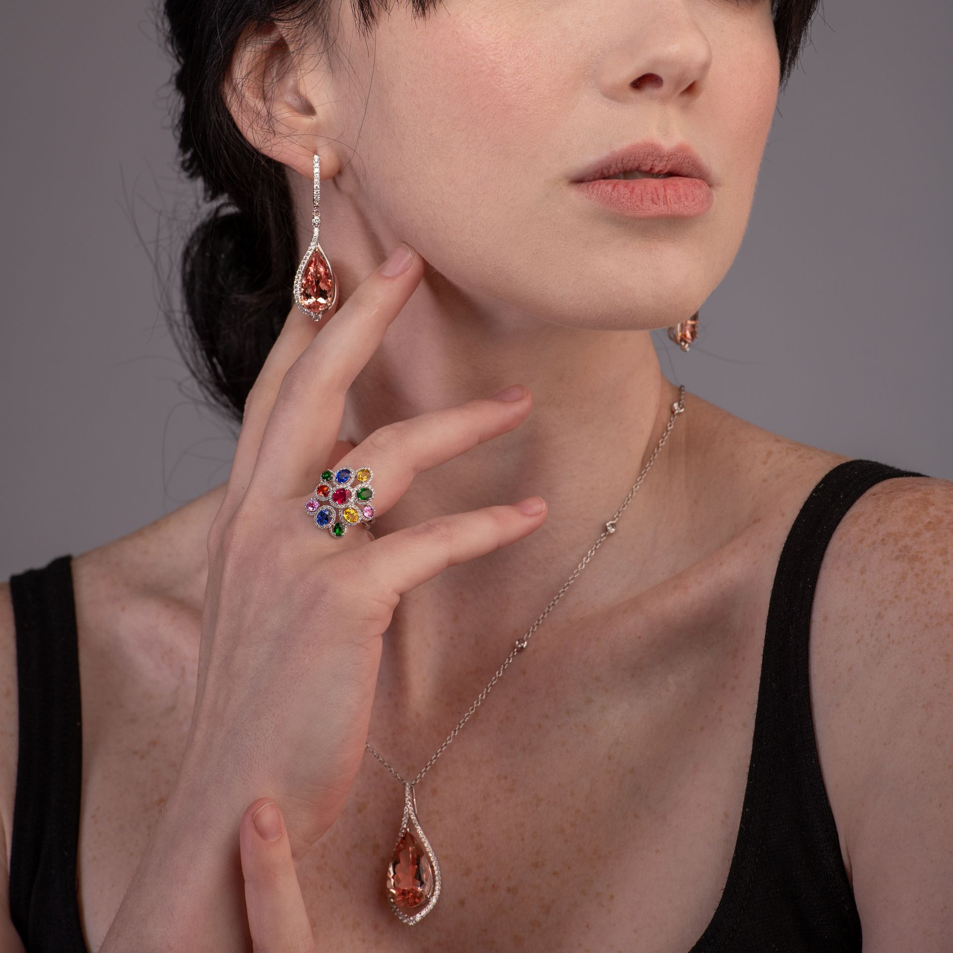 A woman wearing a necklace and earrings has a ring on her finger