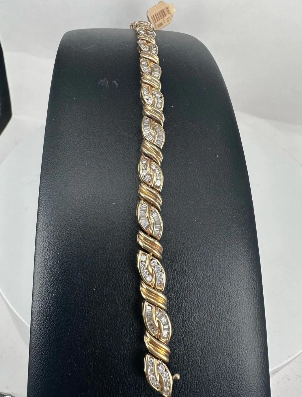 A gold and diamond bracelet is on a black display