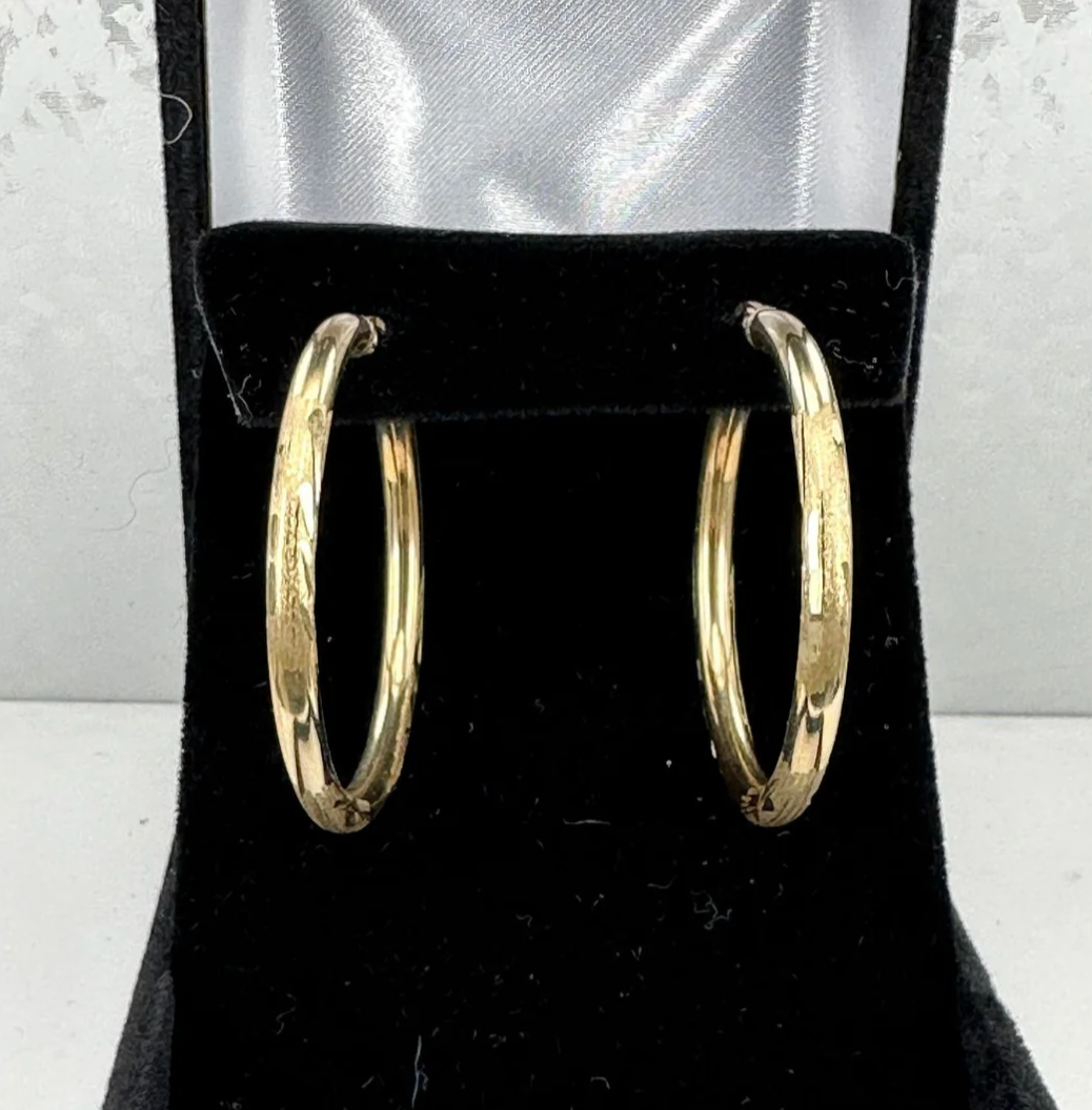 A pair of gold hoop earrings in a black box