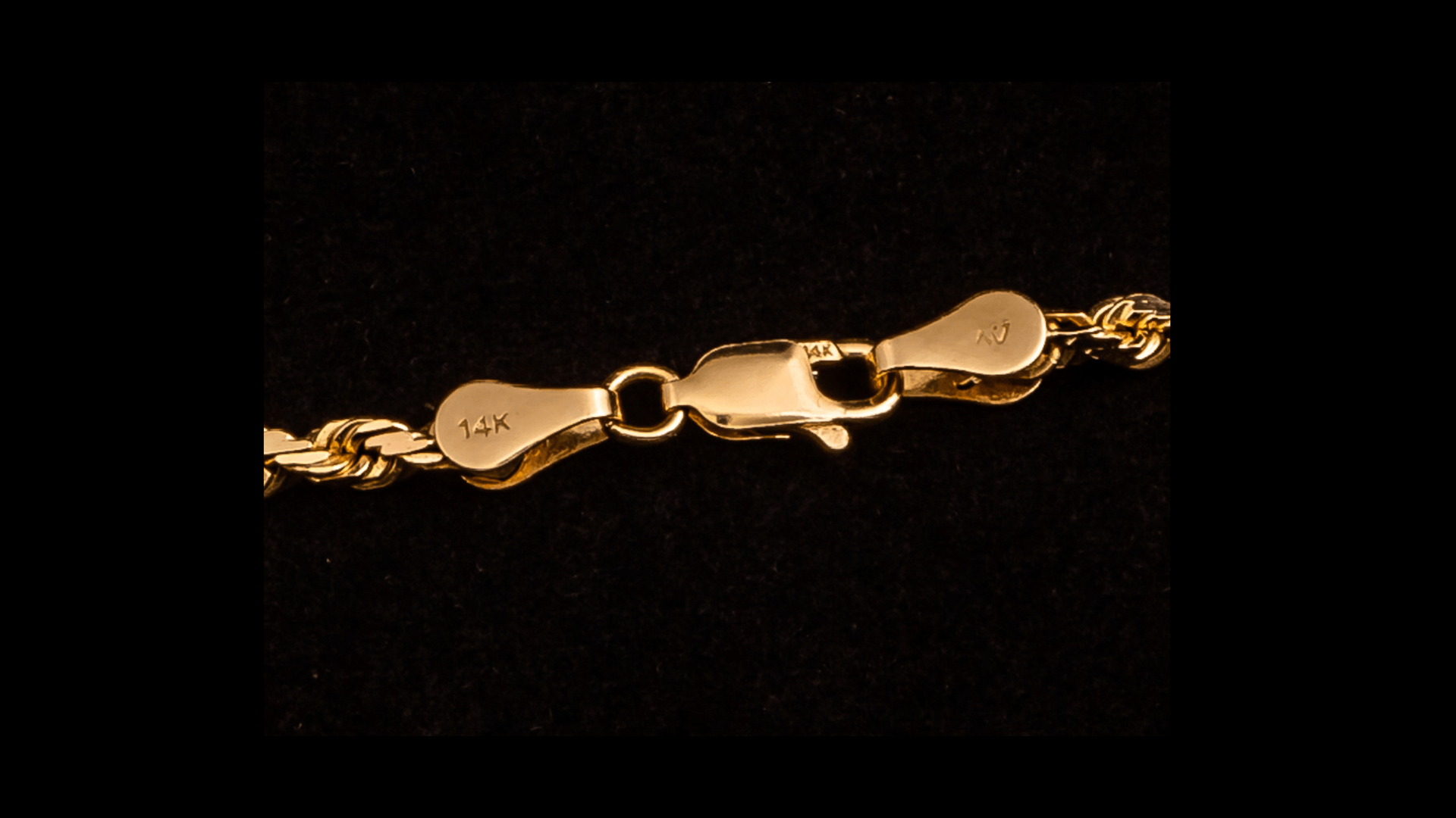 A close up of a gold chain on a black background