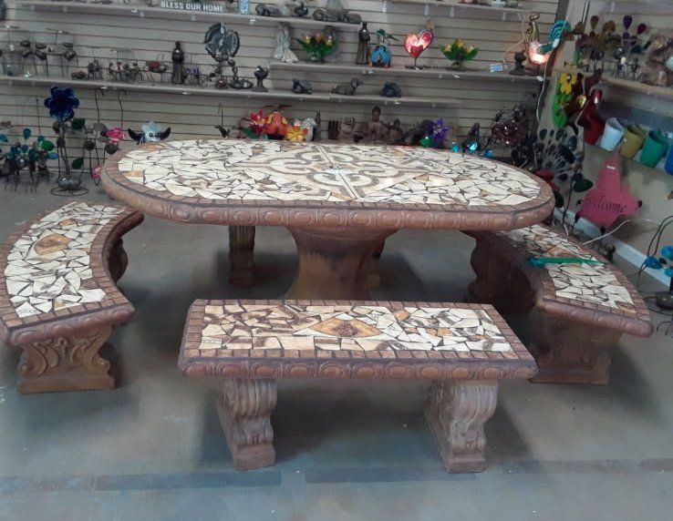 Stone mosaic table and benches displayed on a showroom floor.