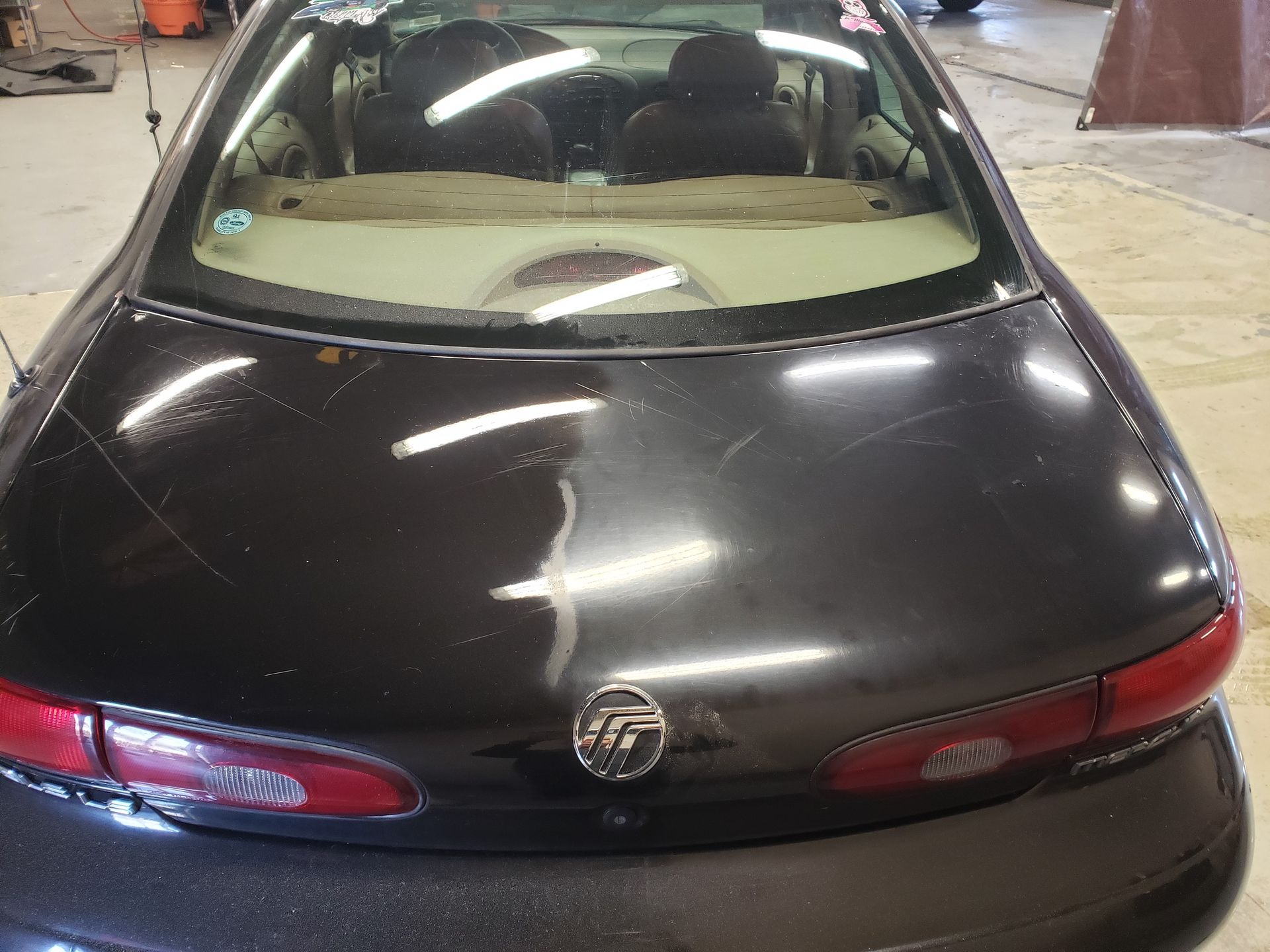Dark-colored car rear view with scratches, taillights, and rear window.