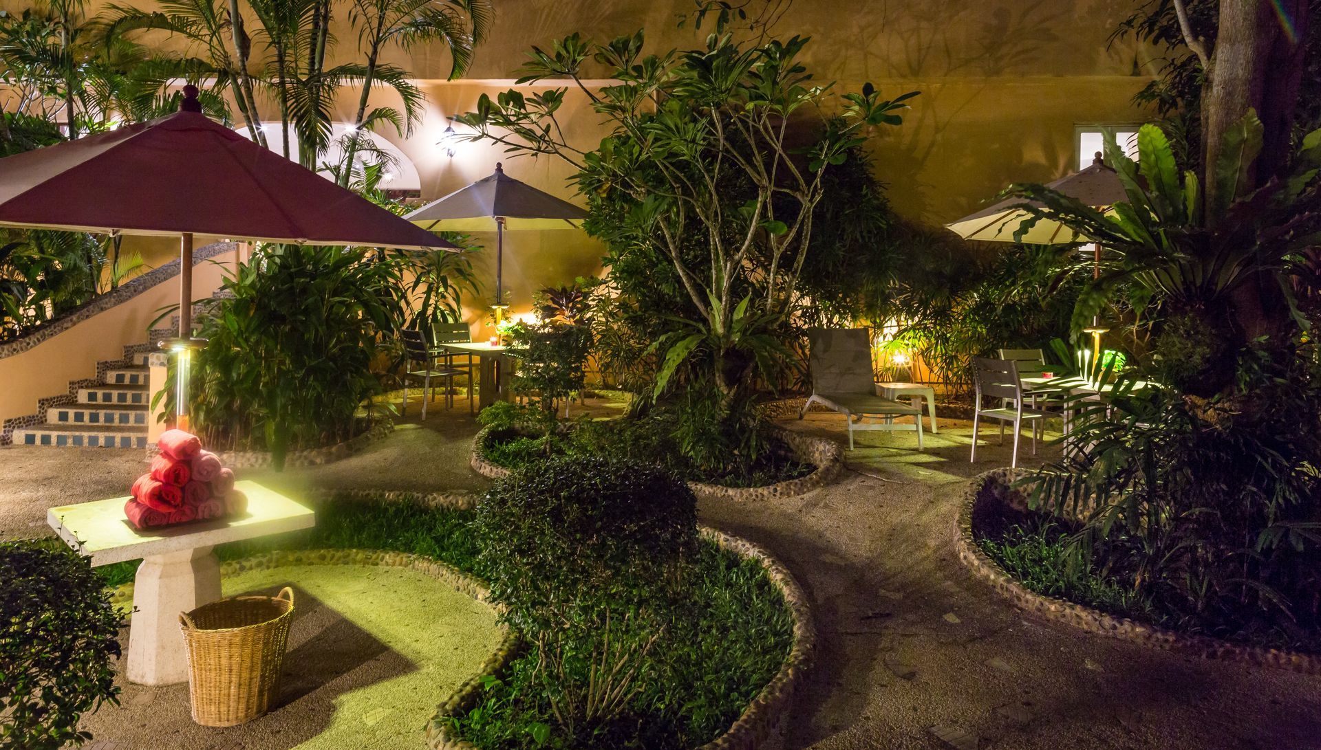 A garden with a table and umbrellas at night