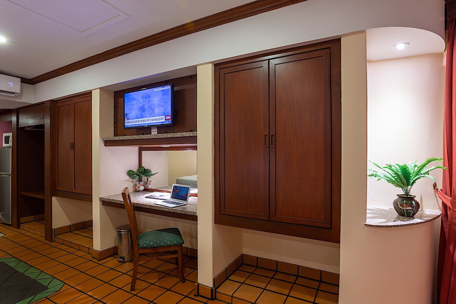 A hotel room with a desk , chair and television.