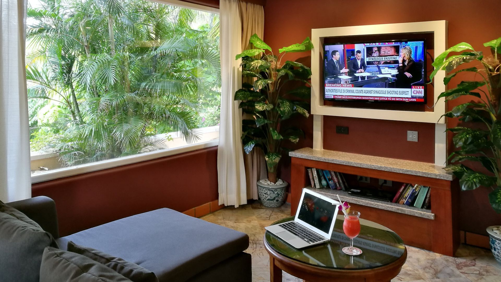 A living room with a couch , table , laptop and television.