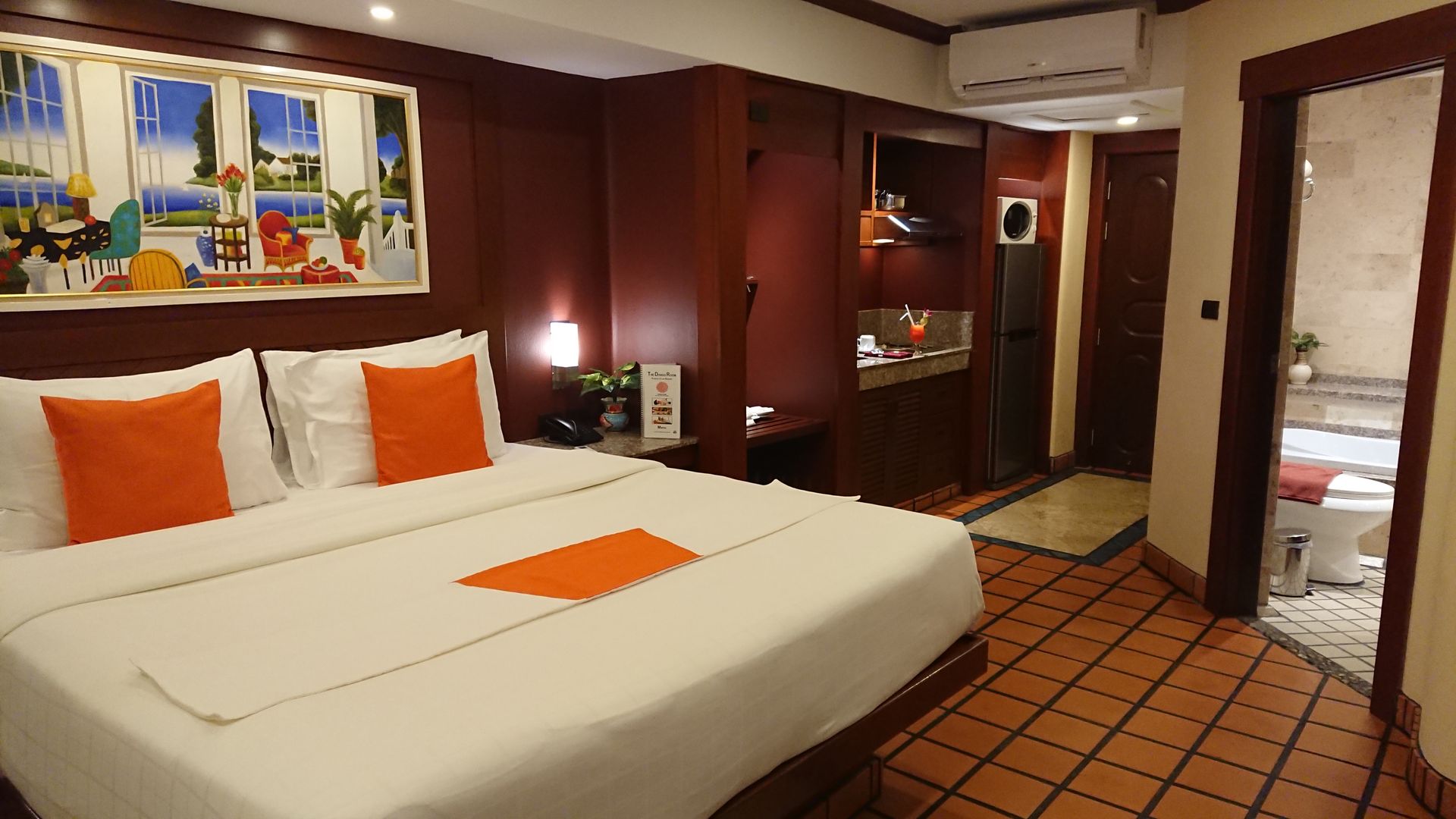 A hotel room with a large bed and orange pillows