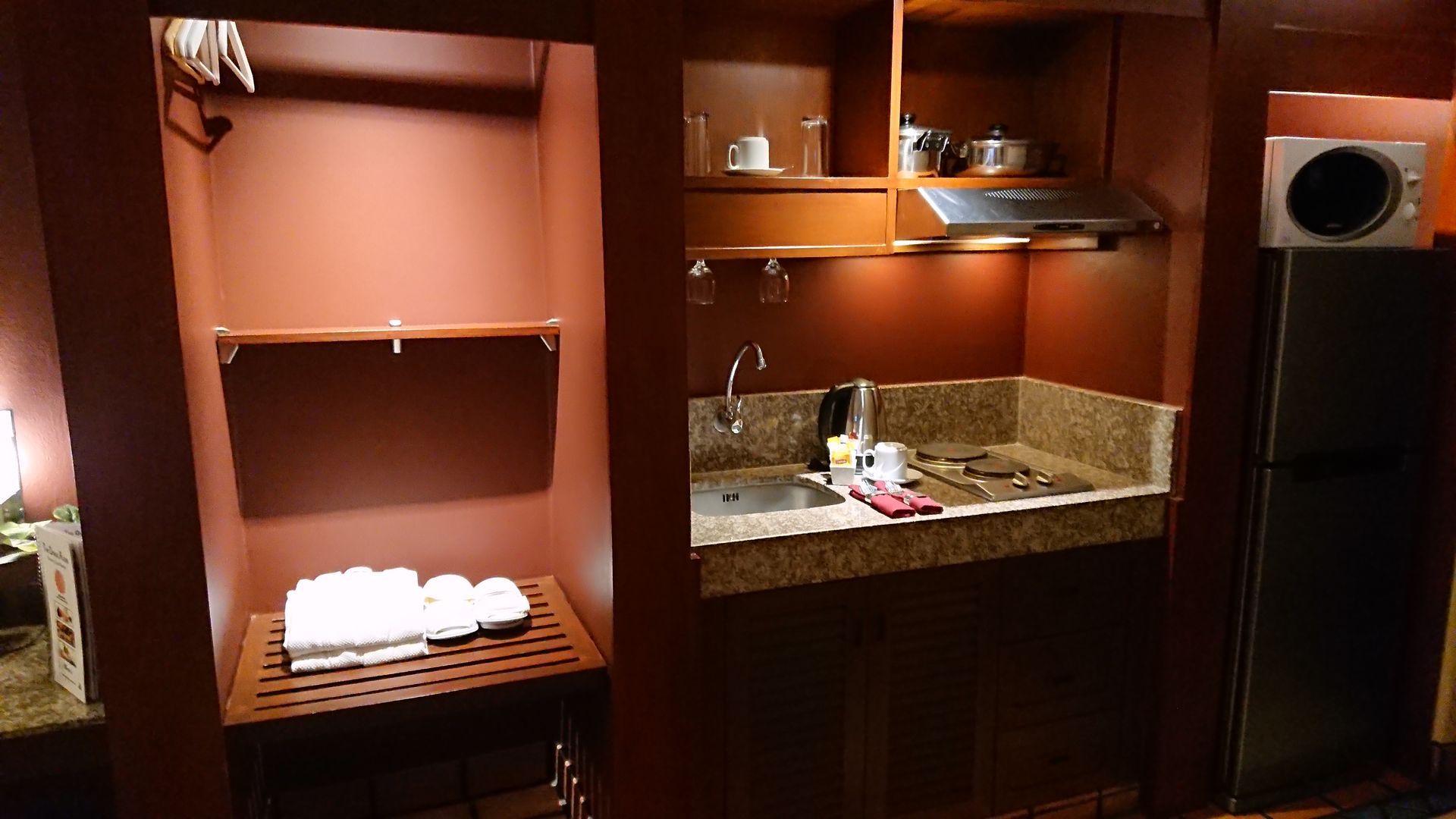 A hotel room with a large bed and a laptop on the nightstand.