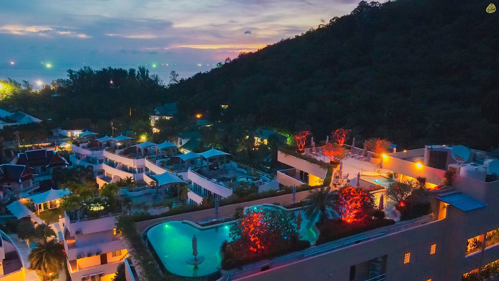 An aerial view of a hotel with a swimming pool on the roof at night.