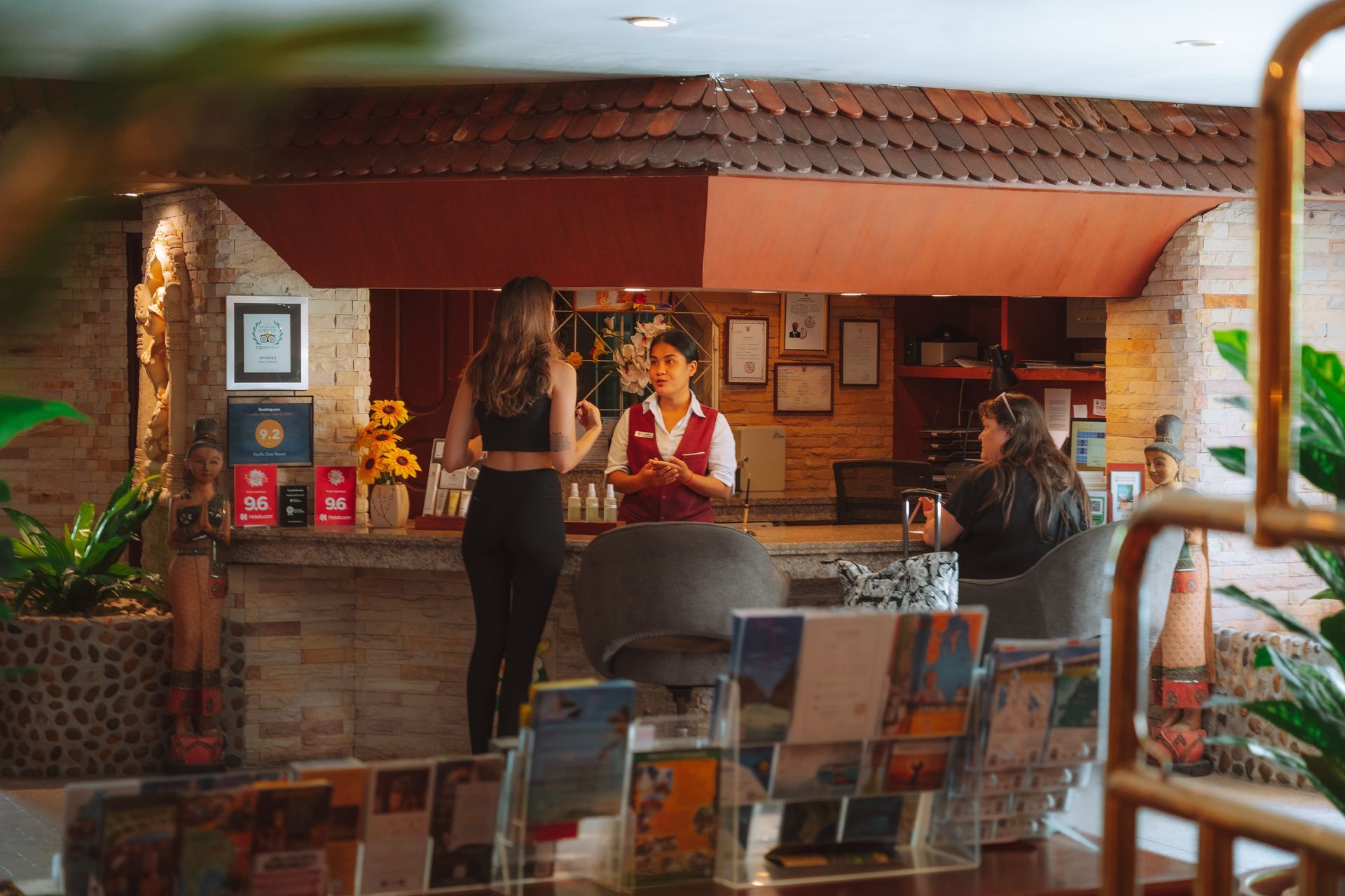 A woman is standing at a counter in a restaurant talking to a man.