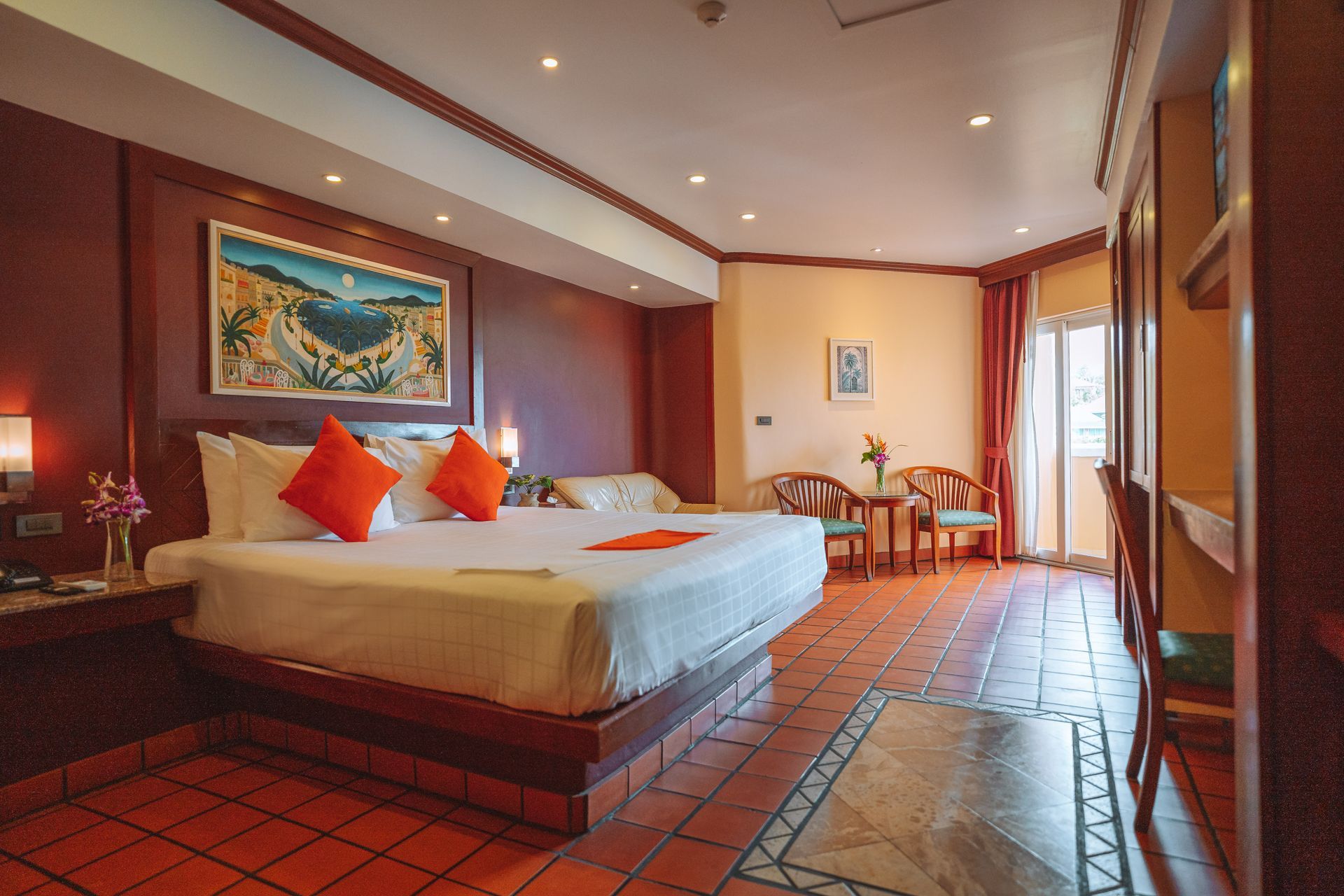 A hotel room with two beds , a table , chairs and a painting on the wall.