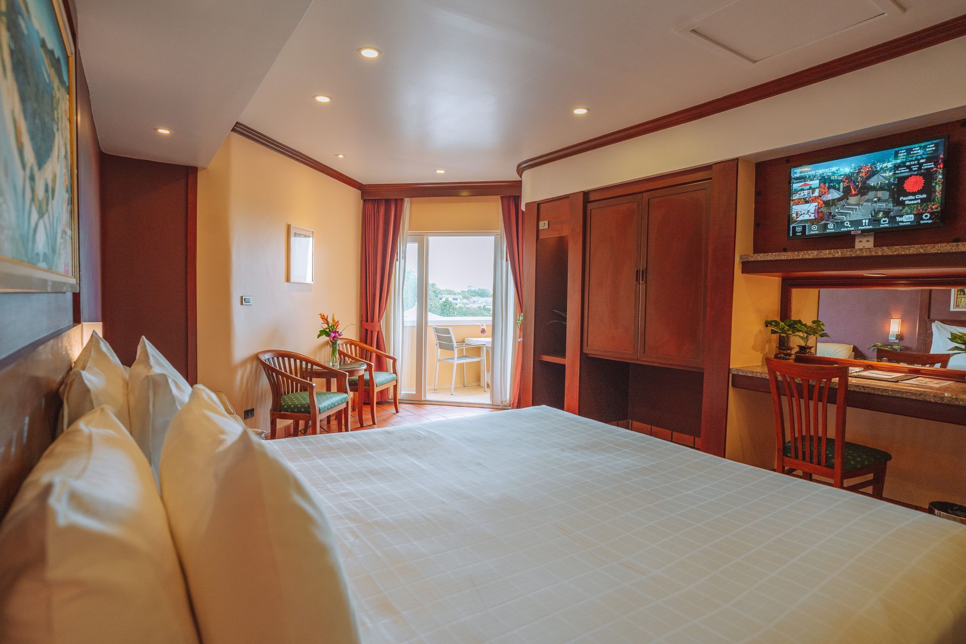 A hotel room with a large bed , chairs , desk and television.