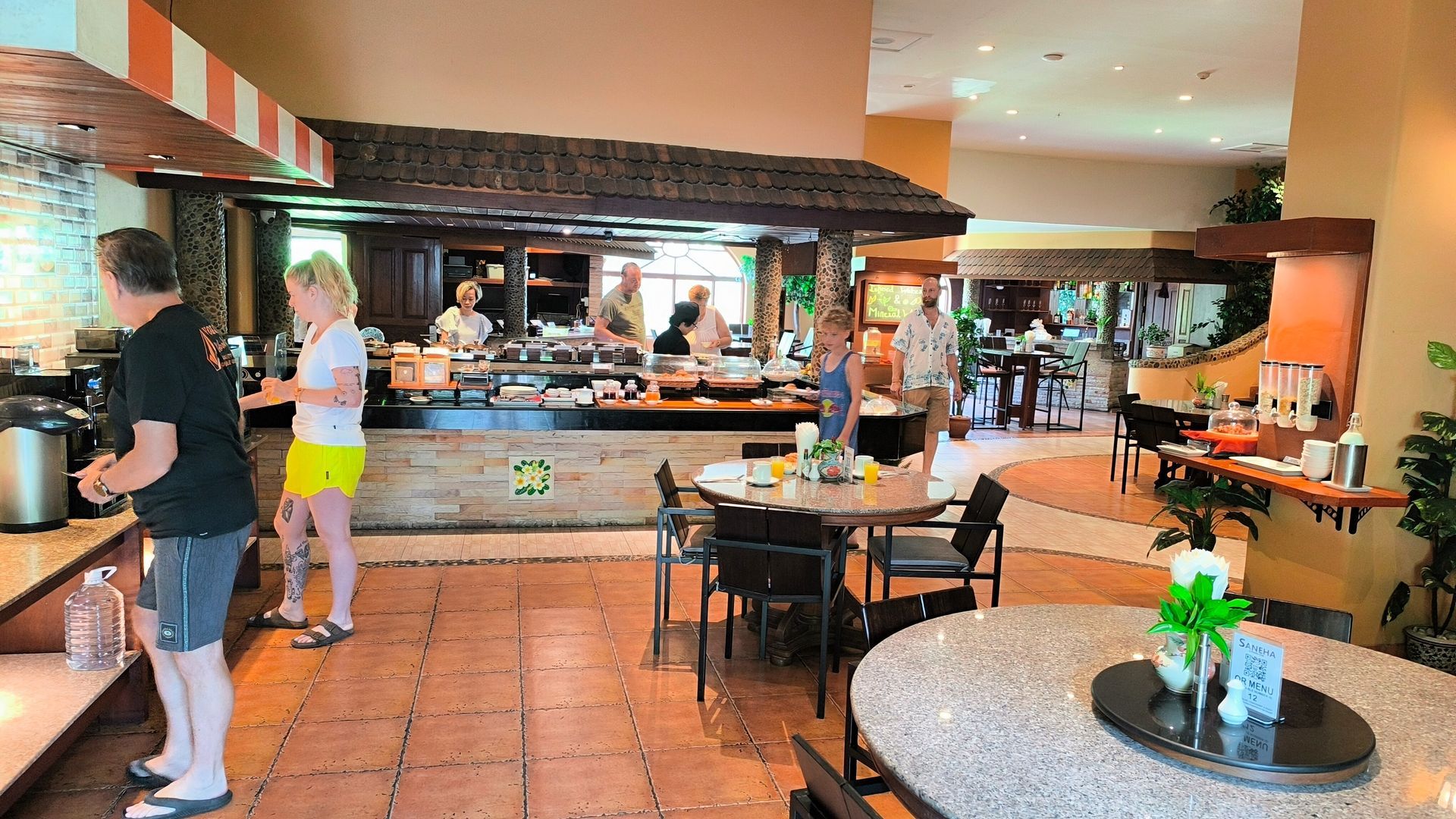 A group of people are standing around tables in a restaurant.