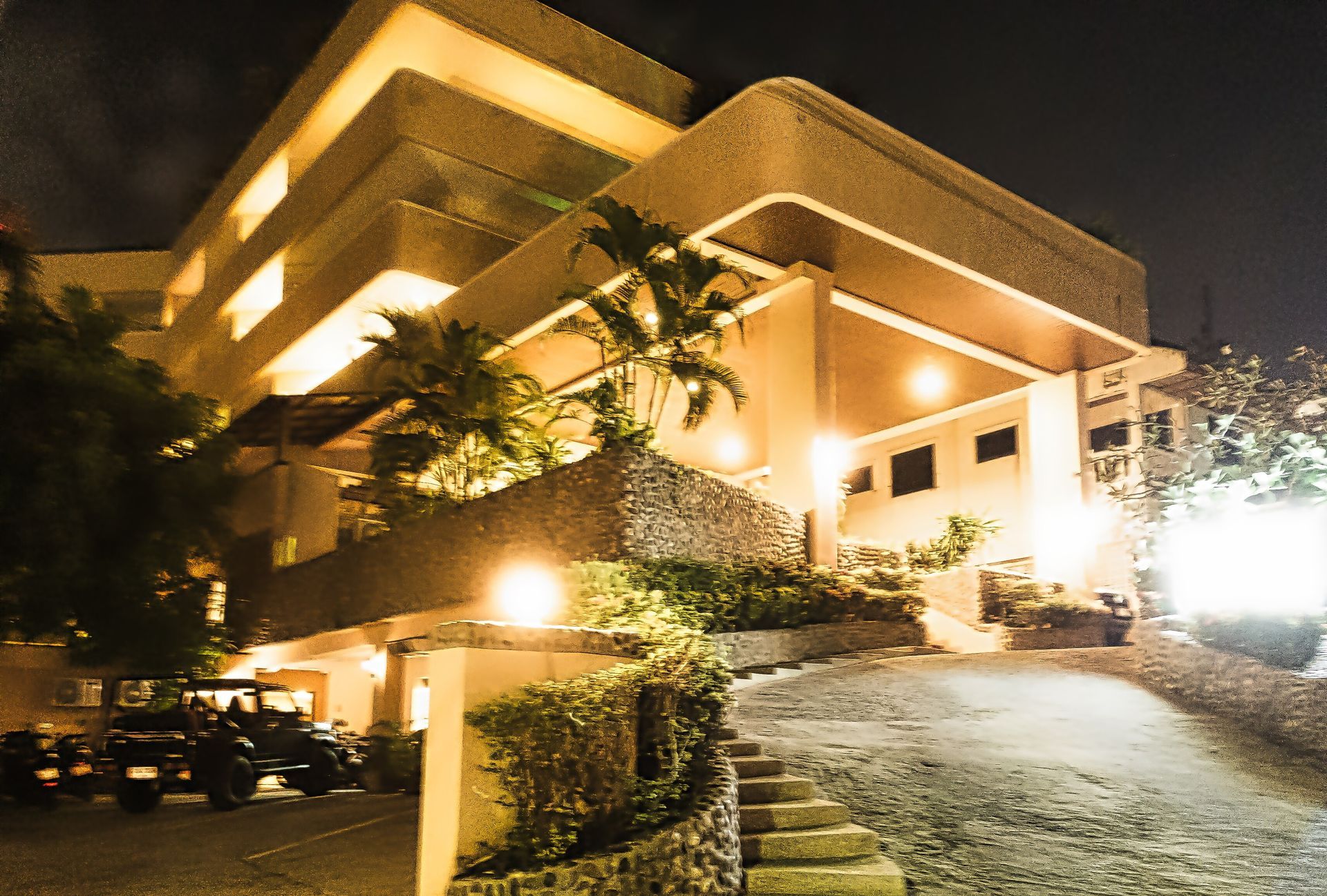A large building is lit up at night with cars parked in front of it