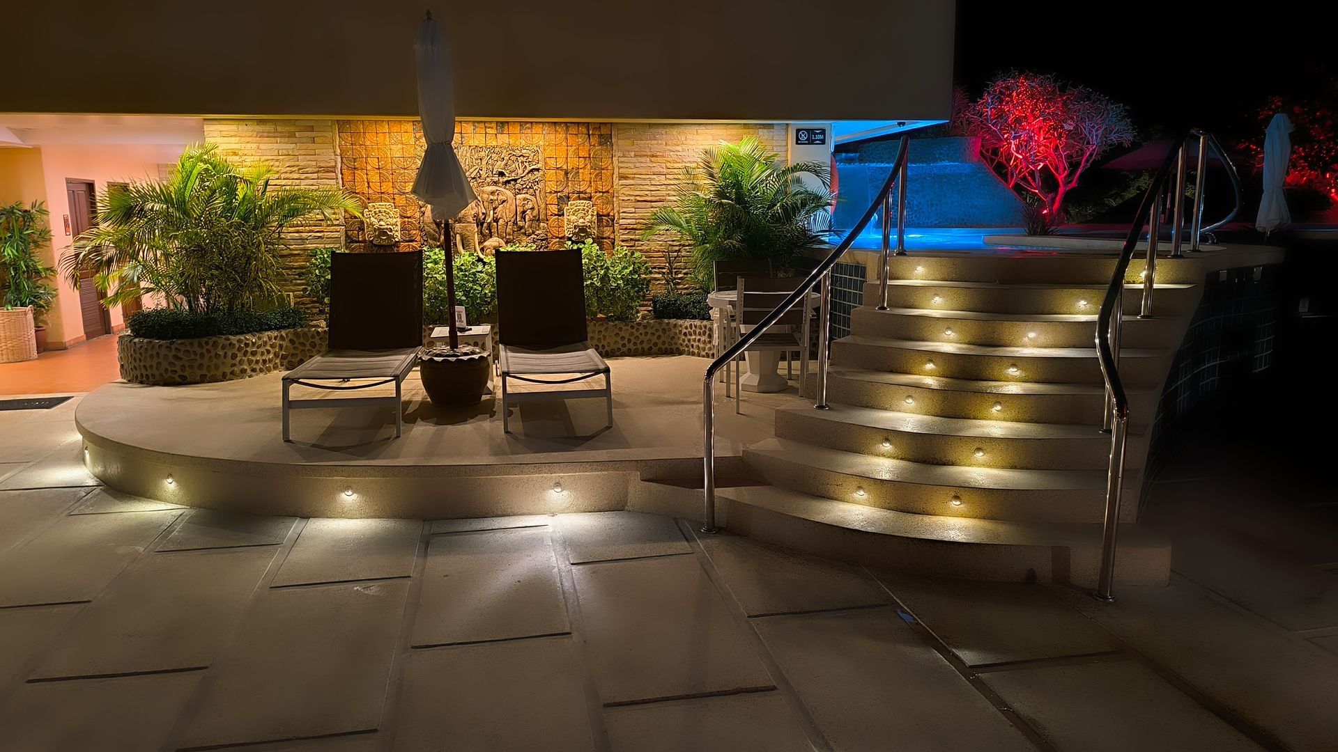 There are stairs leading up to a pool at night.
