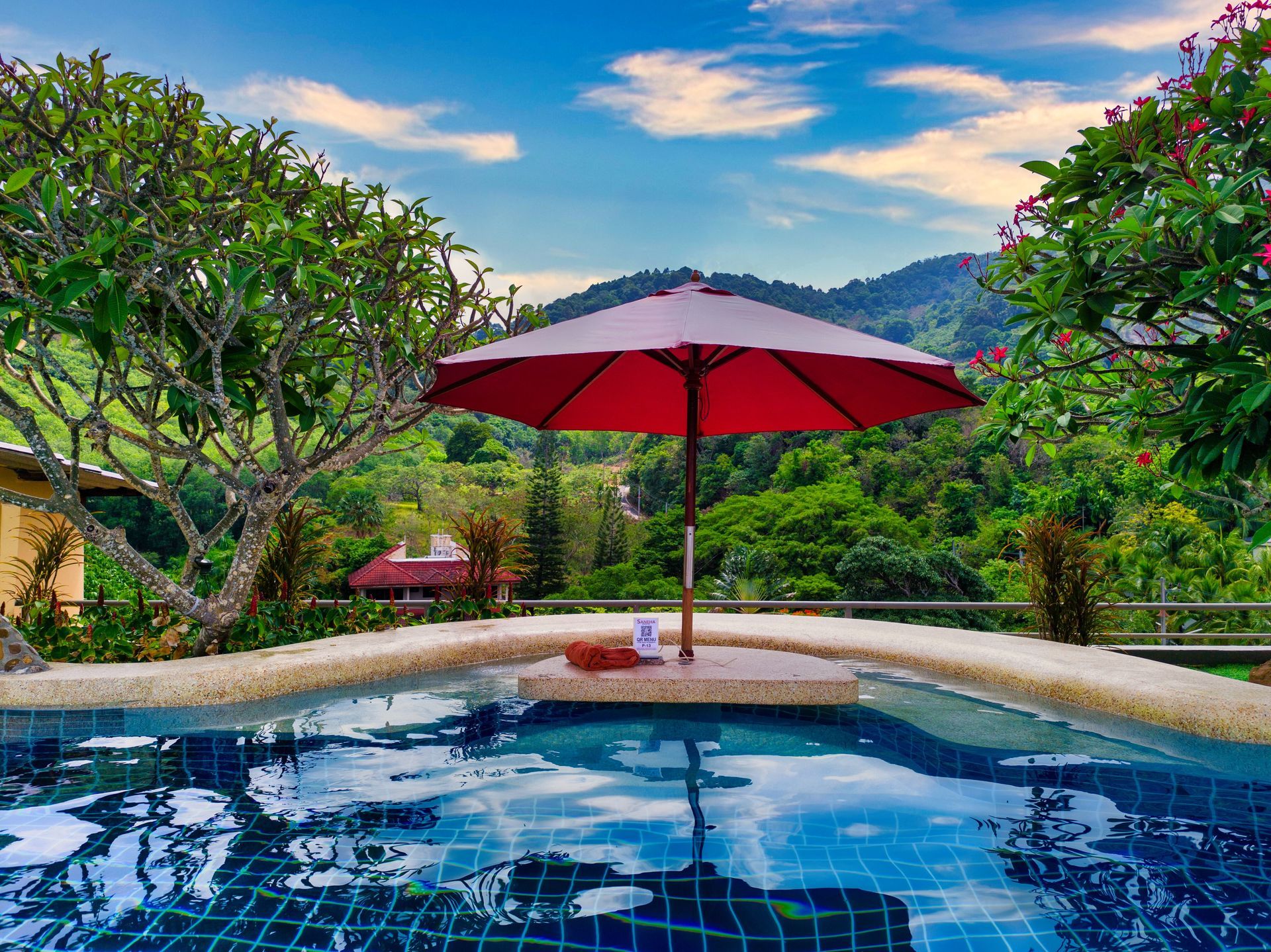 A large swimming pool with a red umbrella in the middle