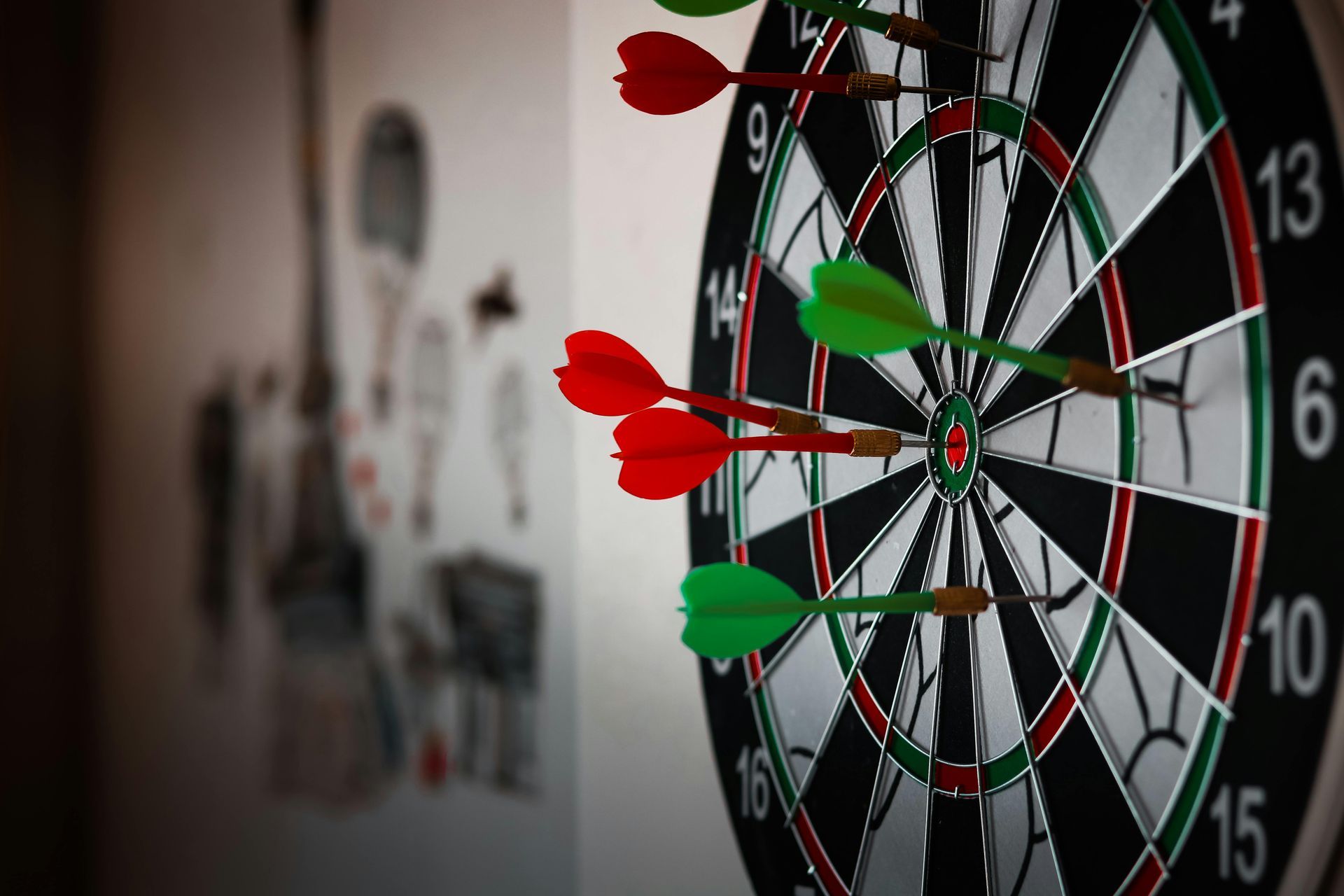 Dartboard with red and green darts embedded.