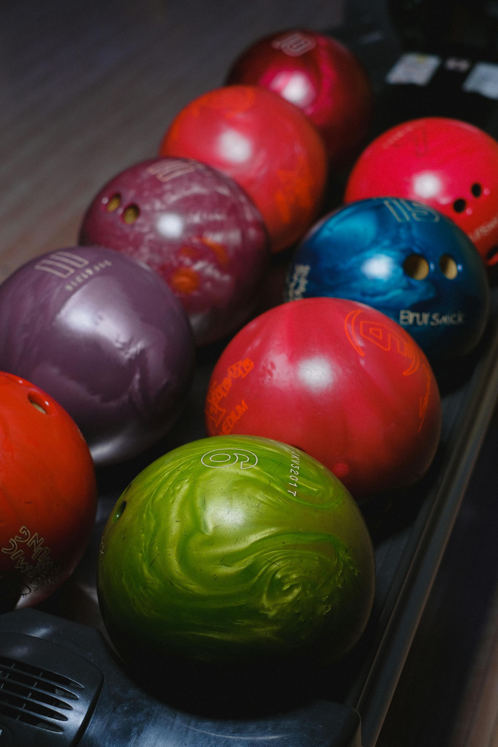 Bowling balls of various colors lined up on a rack.