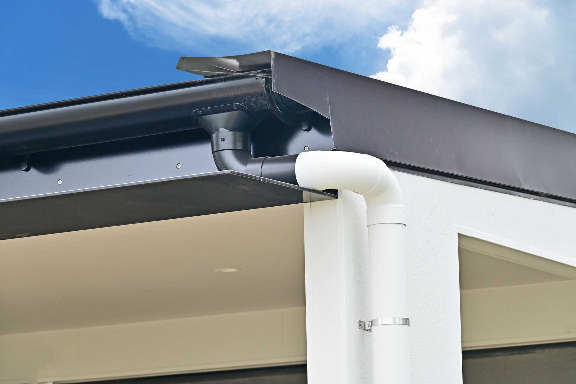 A gutter on the side of a building with a blue sky in the background