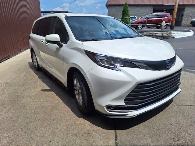 A white toyota sienna minivan is parked in a parking lot.