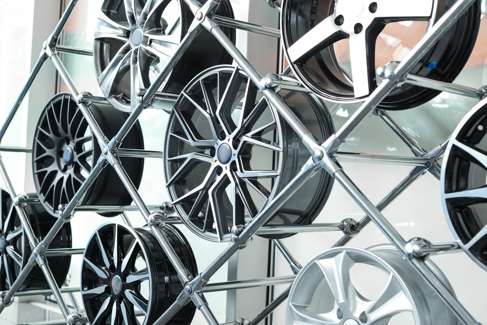 Car wheel rims displayed on a metal rack inside a store, various designs and colors.