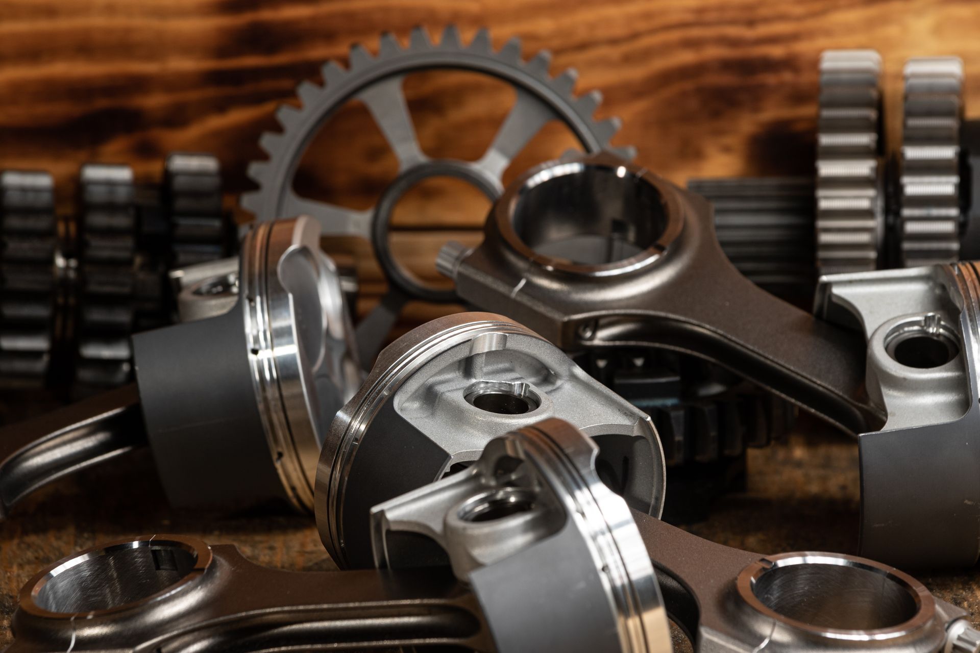 Engine pistons and gears on a wooden surface.