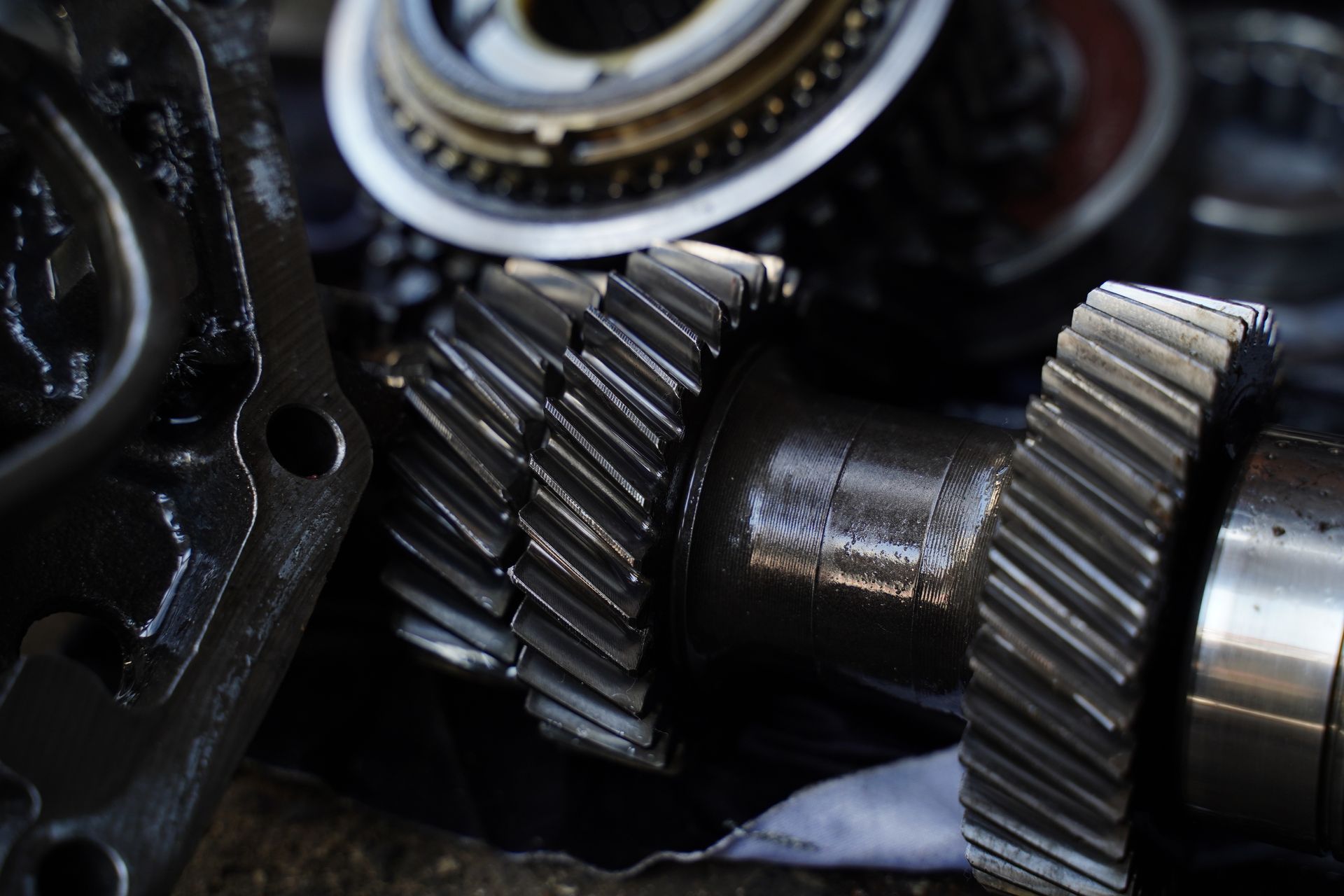 Close-up of disassembled automotive transmission gears, coated in oil.