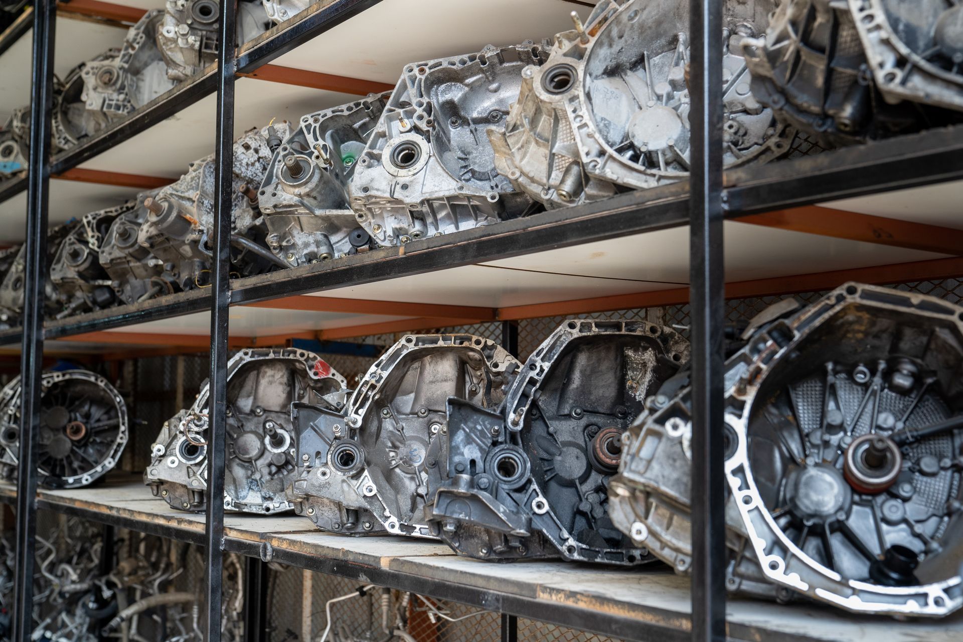 Rows of used automotive transmissions stored on metal shelves.