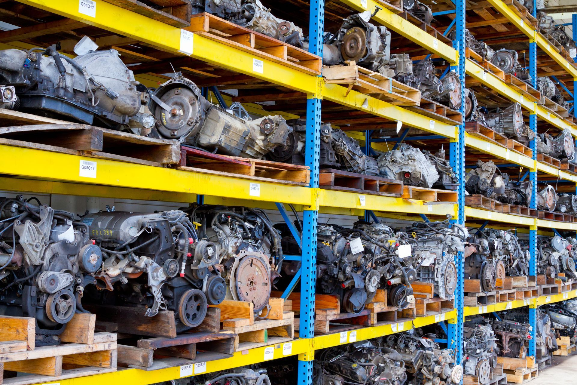 Rows of used car engines and parts stacked on warehouse shelves for salvage