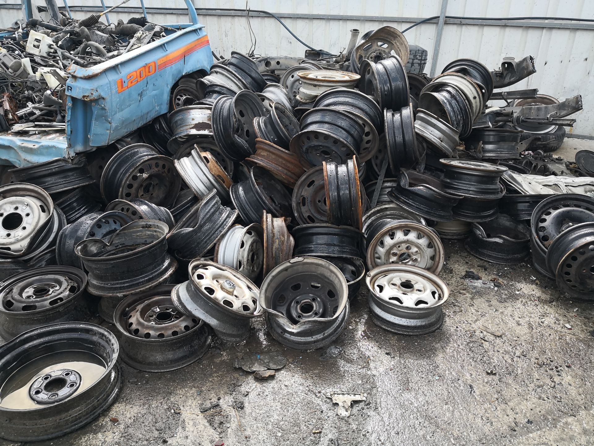Scrap metal rims and auto parts stacked in a salvage yard recycling area.
