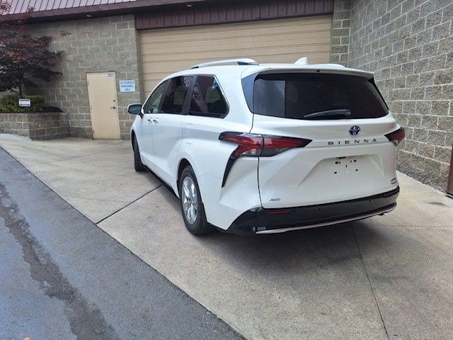 A white minivan is parked in front of a brick building.