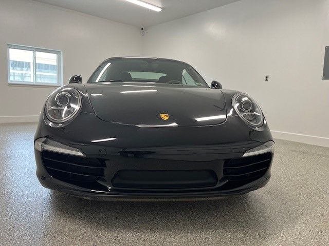 A black porsche 911 is parked in a garage.