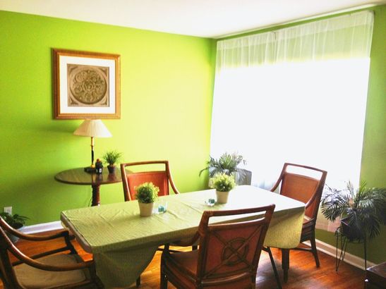 A dining room with green walls and a table and chairs
