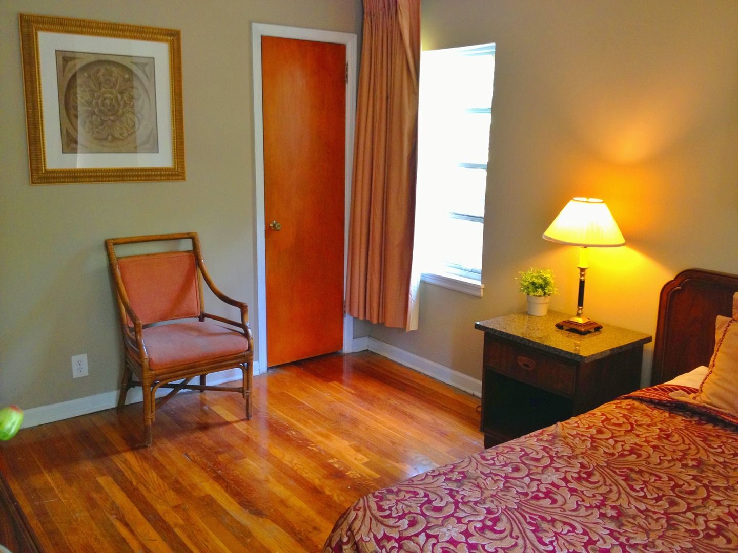 A bedroom with a bed a chair and a lamp
