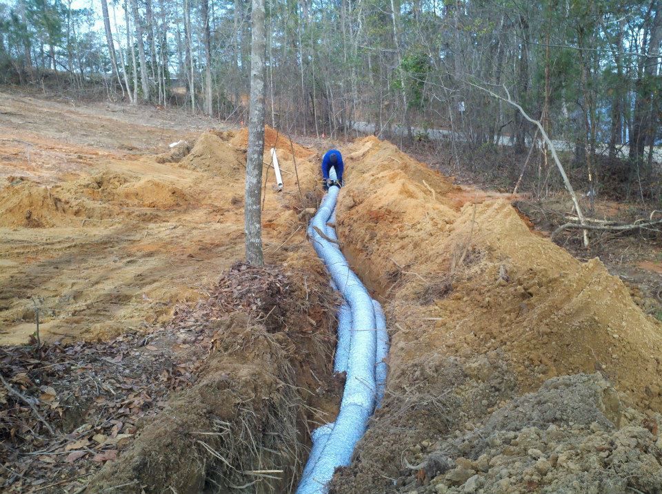 A pipe is being installed in a dirt field.