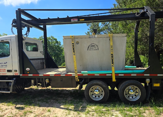 A large concrete tank is sitting on top of a flatbed truck.