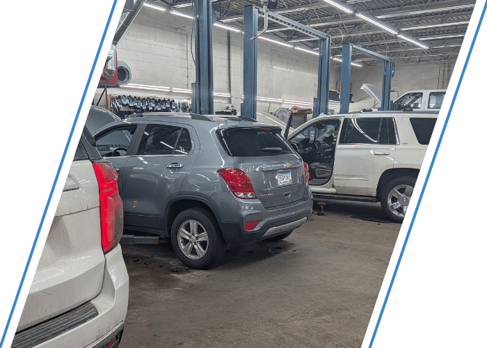 Multiple fleet vehicles inside a professional auto repair shop undergoing maintenance and service.