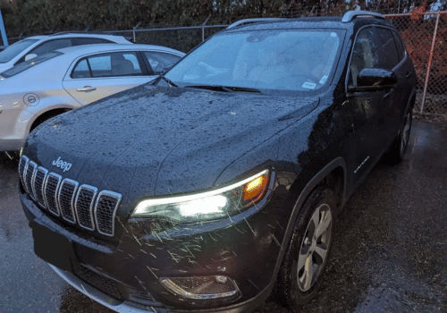 Black Jeep Cherokee SUV parked outdoors in rainy weather