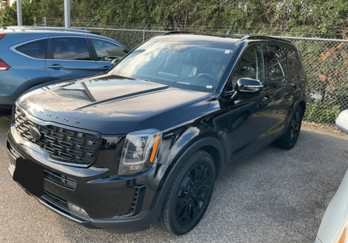 Black Kia Telluride SUV parked outdoors in a parking lot, shown from the front driver's side on a clear day.